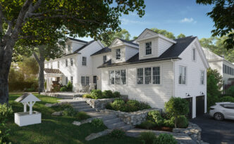 Front view of the restored white clapboard Colonial in Needham with black roof, dormers, stone walls, granite steps and the restored wishing well on the lawn